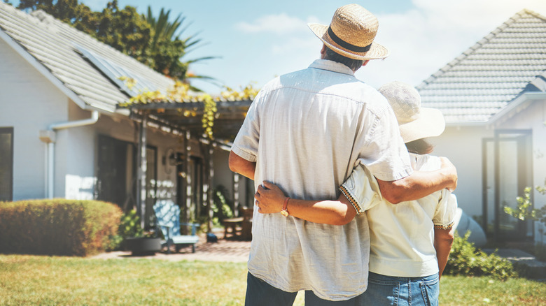 two people hug and look at house