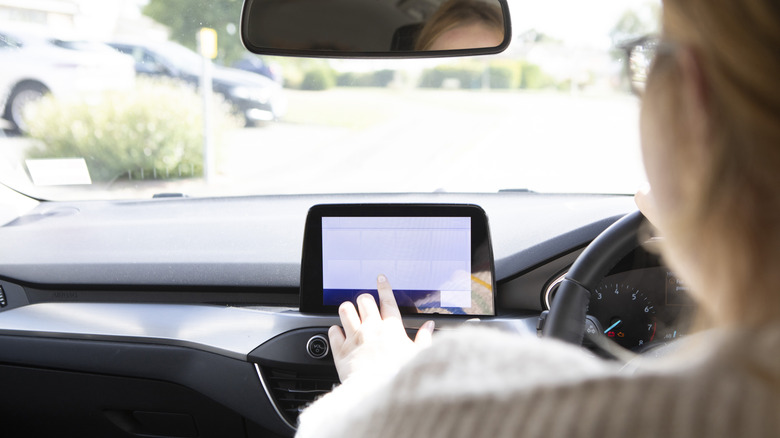 A woman setting up a telematics device on the dashboard of her car.