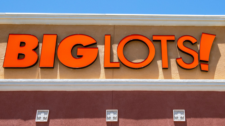 Close-up on a Big Lots! storefront's orange sign on a sunny blue day.