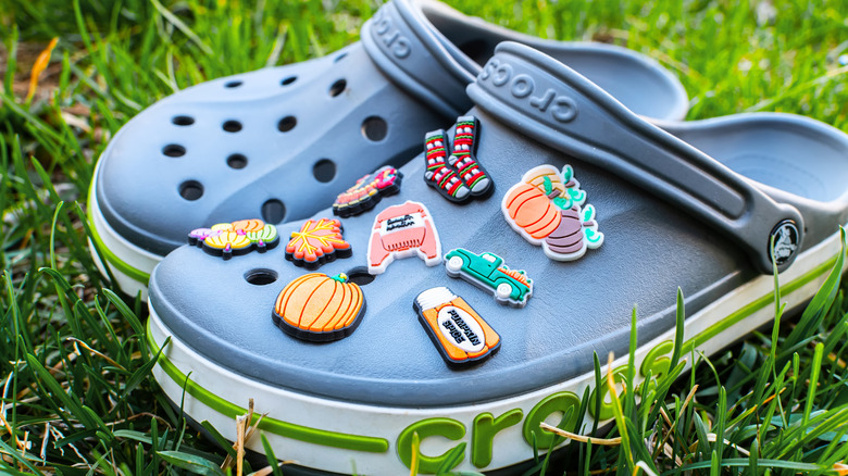 Pair of crocs with various fall-themed buttons in the grass