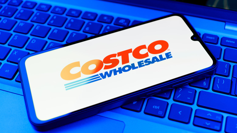 Costco Wholesale app on phone homescreen, resting on top of a laptop keyboard