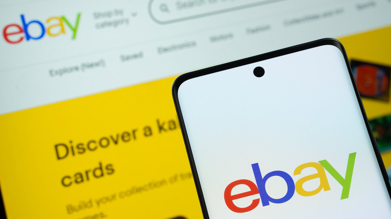 The eBay logo displayed on a smartphone screen and a computer screen in the background.