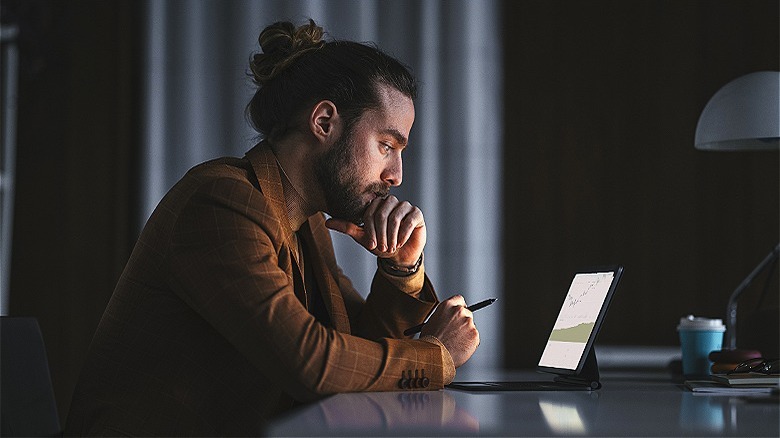 Person viewing stocks, darkened room