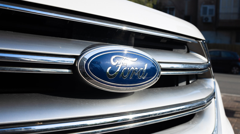 A close-up of the blue Ford emblem on a silver radiator grille of a white car.