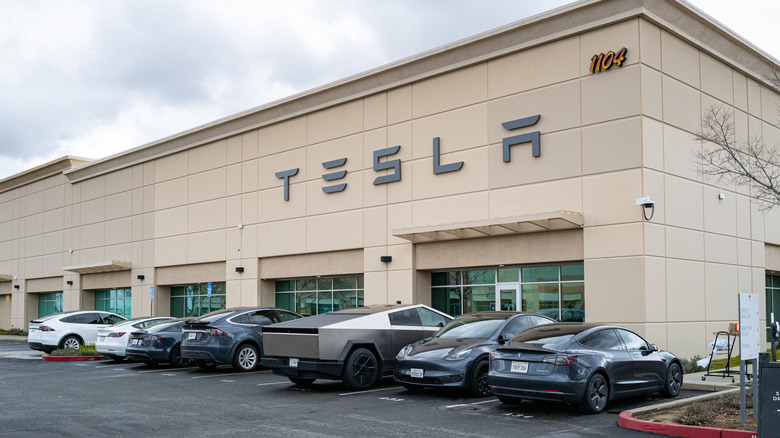 Exterior entrance of a Tesla Service and repair center with cybertrucks outside.