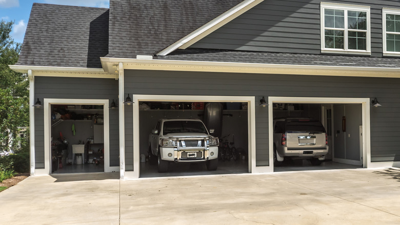 The side view of a large house with muliple cars in the garage