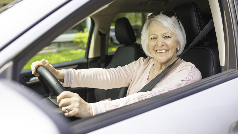 A happy and smiling senior woman in white car.