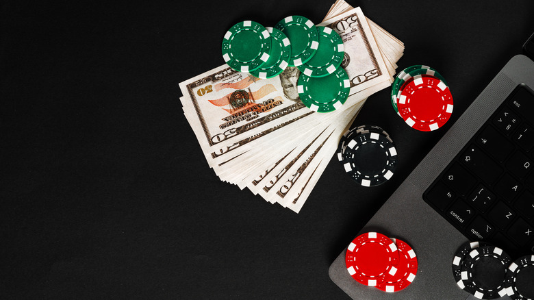 Money and casino chips on a laptop