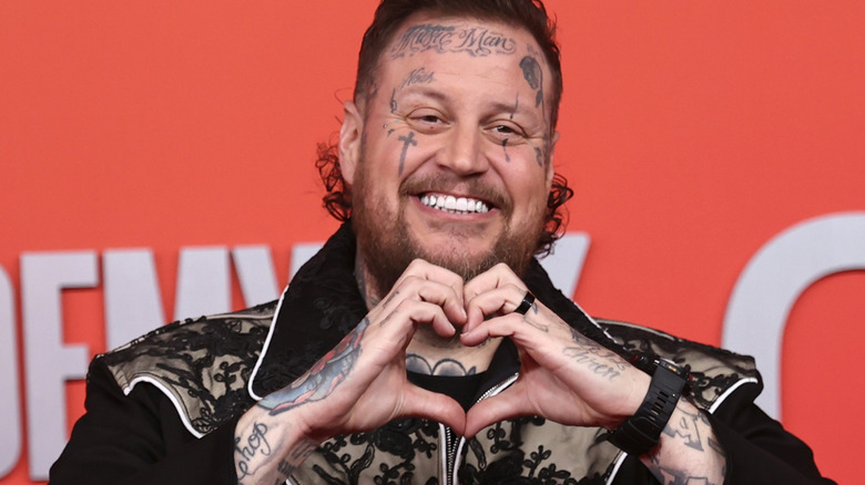 Jelly Roll makes heart gesture with hands and smiles