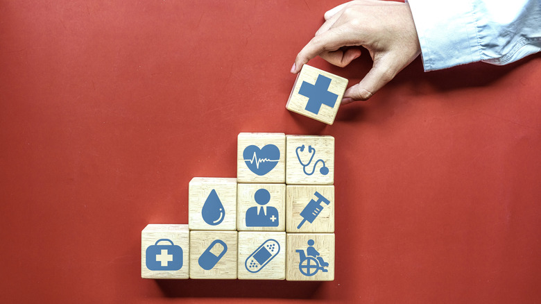 Person staking cubes with health health related icons.