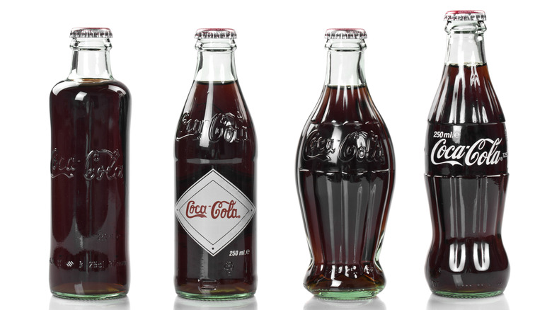 Four Coca-Cola bottles in different shapes and styles