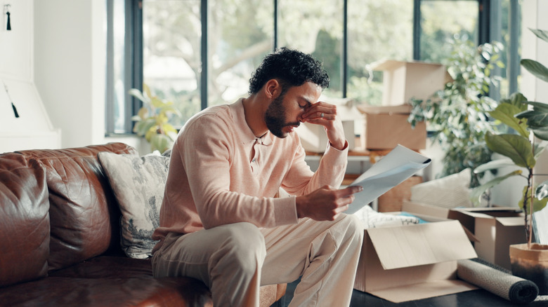 Worried man looking at paper with boxes around him