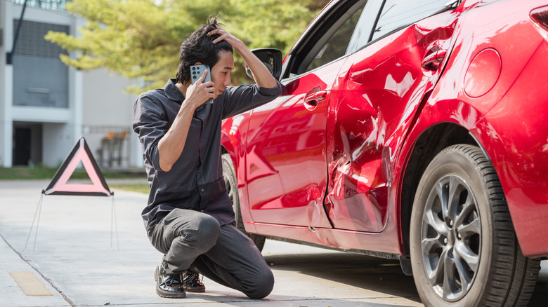 Frustrated man looking at car accident damage