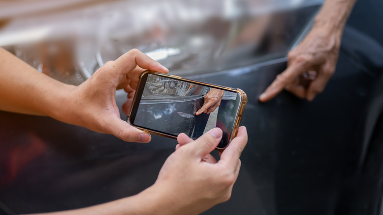 Person photographing damage on a car