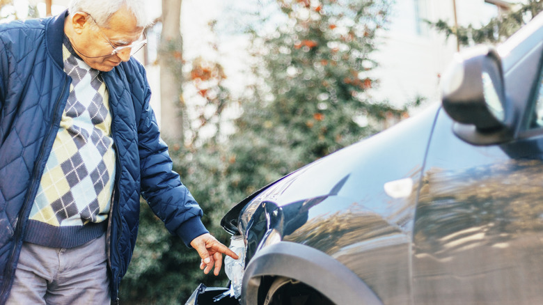 Senior looking at a car with damage