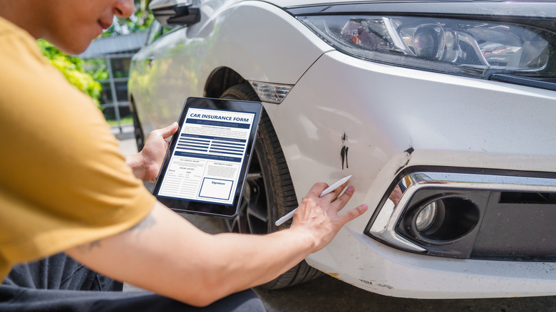 Man inspecting damage on a car and completing a form