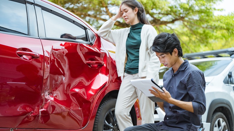 Woman and insurance adjuster looking at auto damage