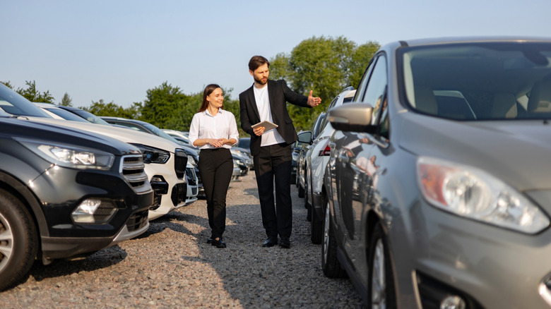 Two people walking down a car dealership lot