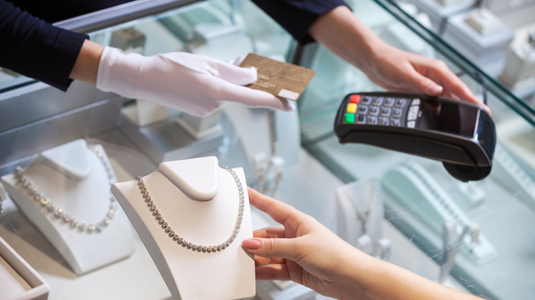 woman buying diamond necklace and paying with hold credit card