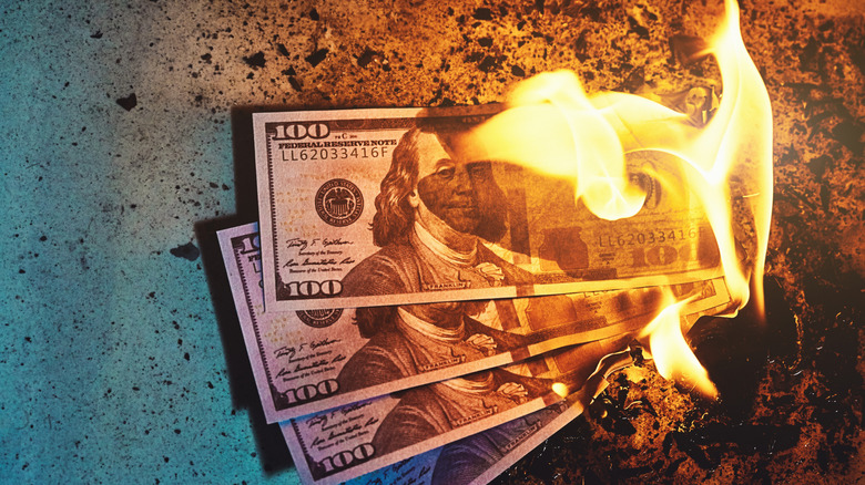 Four $100 bills on fire.