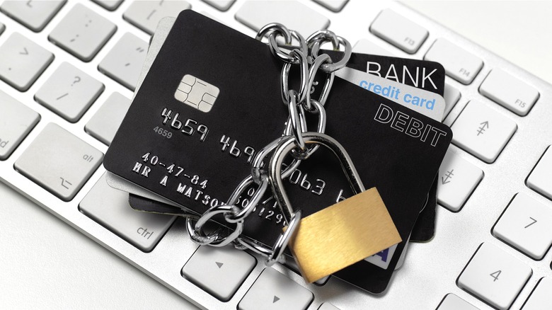 Stack of debit and credit cards padlocked atop a keyboard