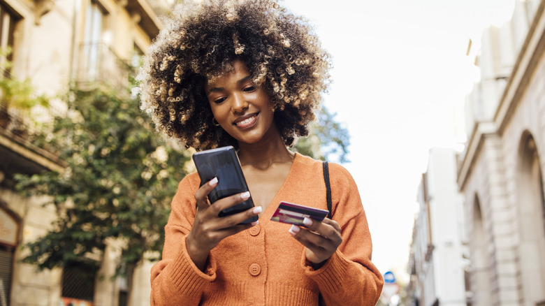 Woman looking at credit card while online shopping
