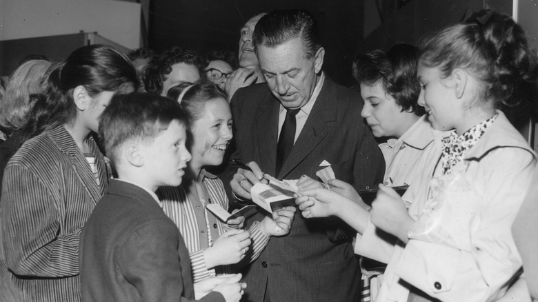 The late Walt Disney signs autographs for children