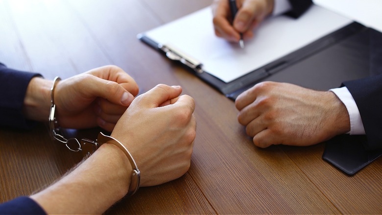 Person with handcuffs, taking notes