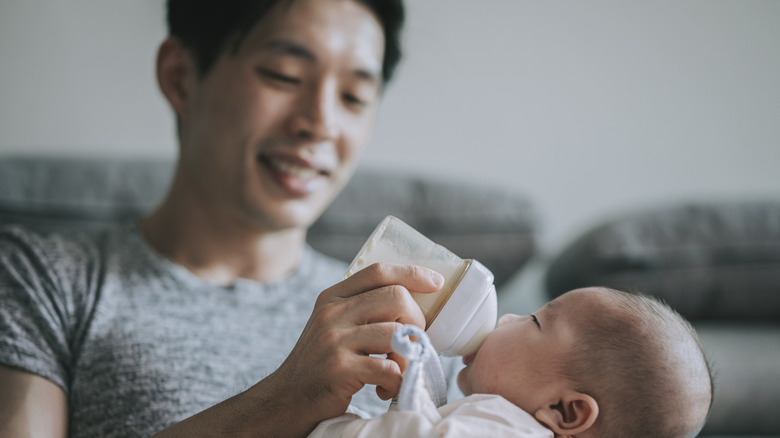 Man bottle feeding infant