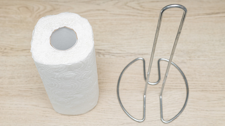 A roll of paper towels next to empty metal paper towel holder