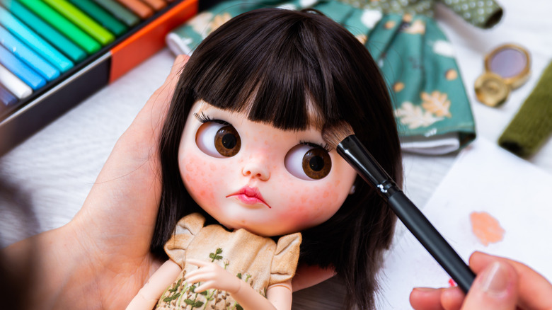wide-eyed doll with blue eyes and pink lips