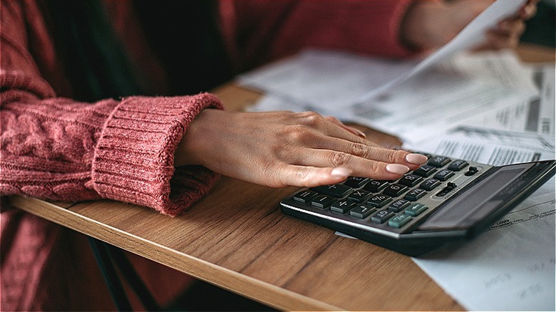Person calculating bills with calculator