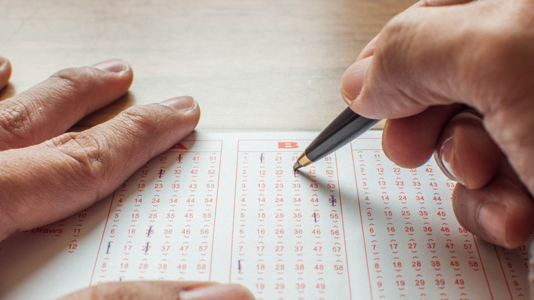 Person filling in lottery numbers on a ticket