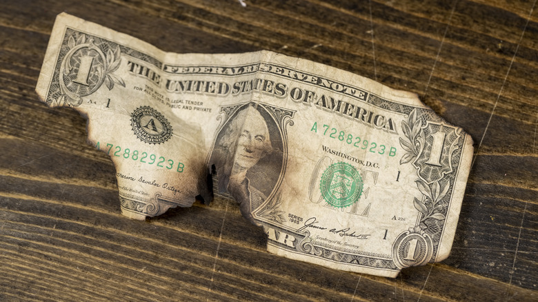 Burnt U.S. one dollar bill on a wooden surface