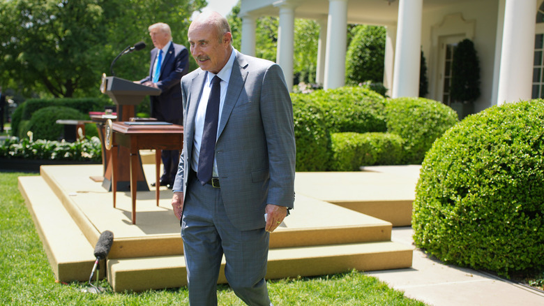 Phil McGraw leaves a White House podium as President Donald Trump speaks in May 2025.