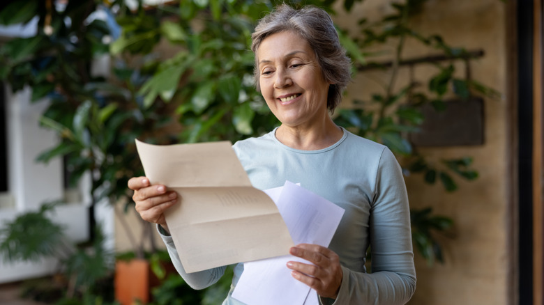 A mature woman smiling while reading a letter