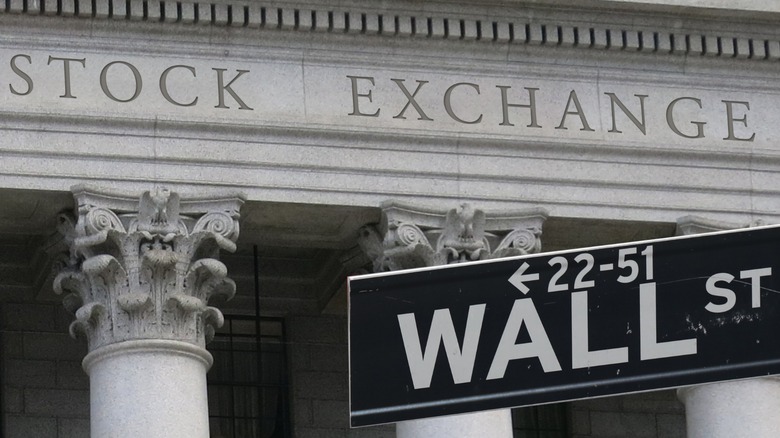 The historic stock exchange building in New York City's financial district seen behind a sign for Wall Street.