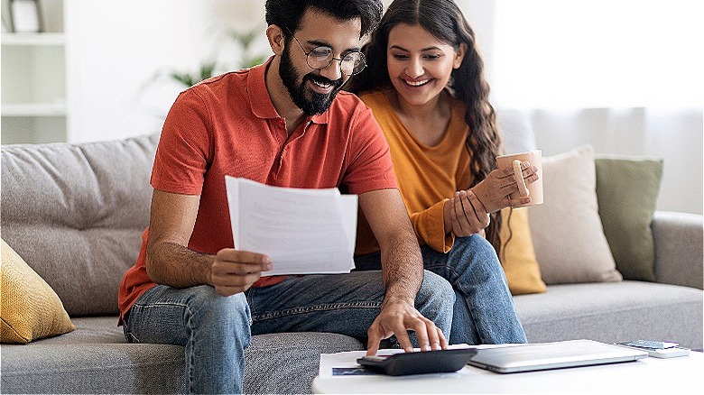 Couple smiling while calculating finances