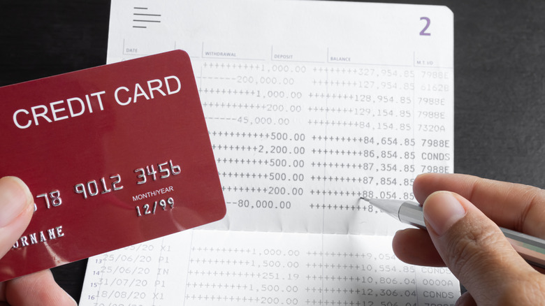 one hand holds a credit card and the other a pencil above a statement