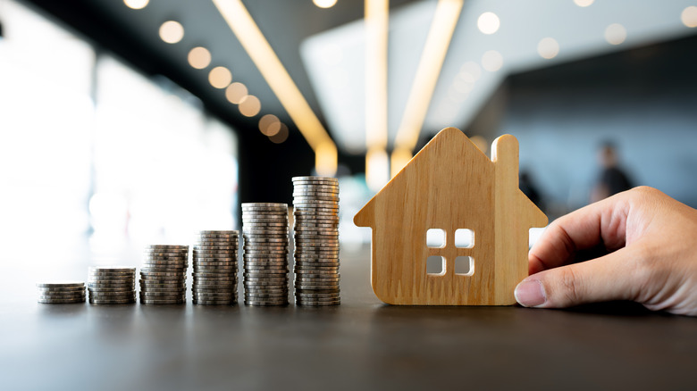 stacks of coins beside wooden cut-out of a house