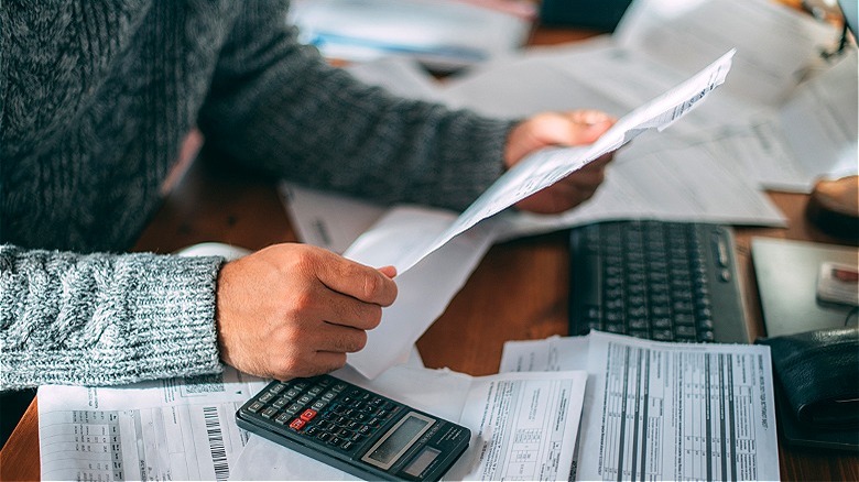 Person reviewing paperwork, making calculations