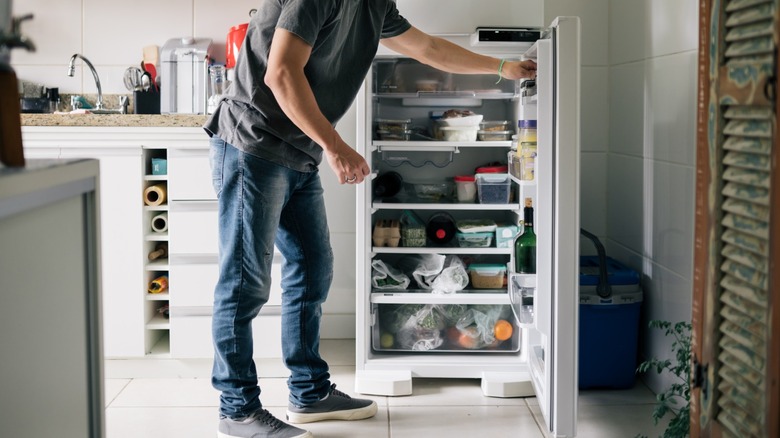 Man opening fridge full of containters in a kitchen