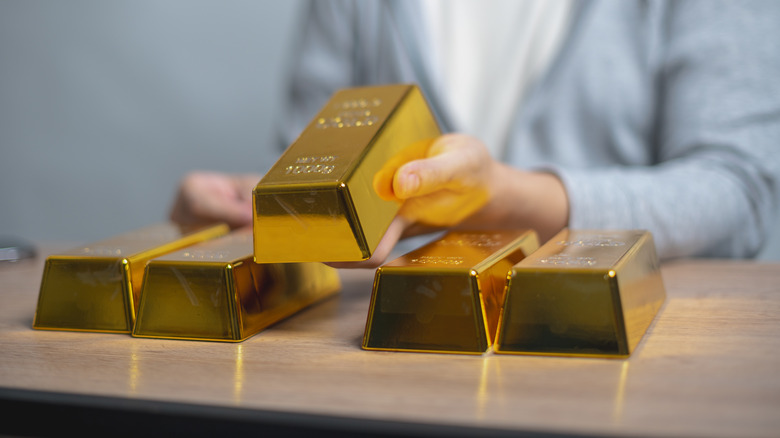 Person stacking gold bars on a table