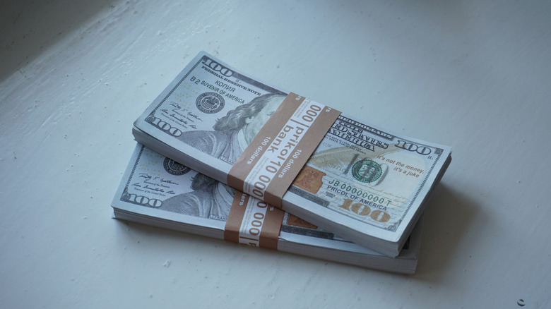 two bundles of hundred dollar bills places against a white background