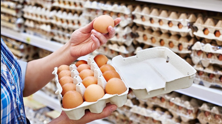 Hands of a woman holding eggs in a supermarket