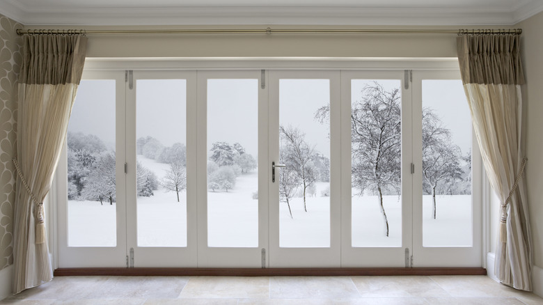 Window curtains opened to reveal snowy conditions outside