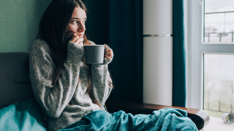 A woman sitting with tea next to window