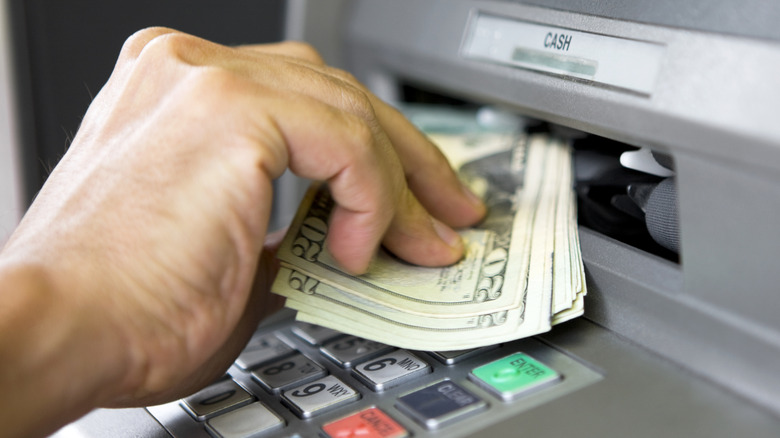 An older person taking cash out of an ATM