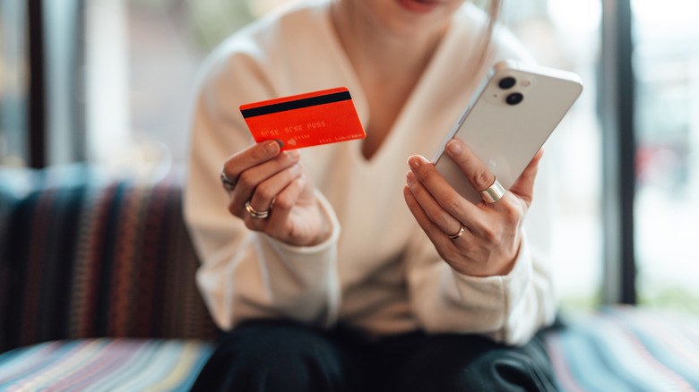 woman holding a credit card and phone