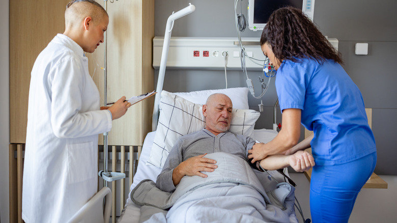 Elderly man in a hospital bed with medical personnel around him